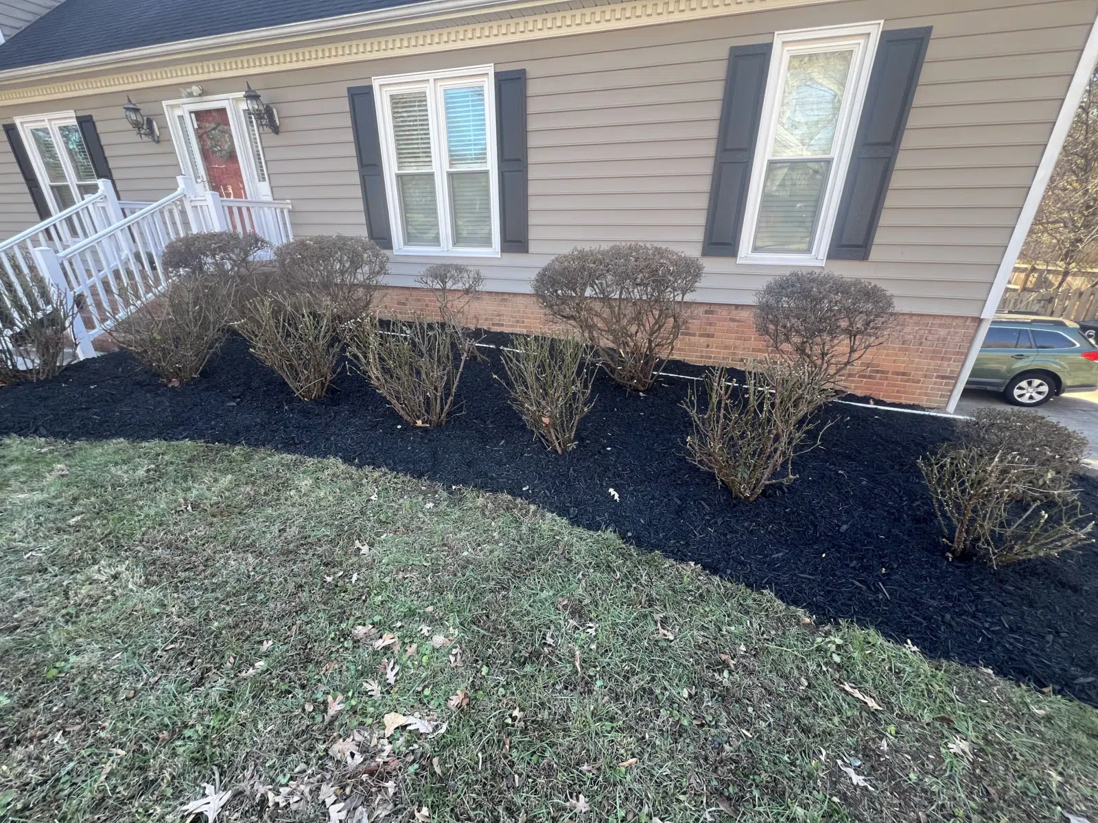 Neatly trimmed shrubs over fresh black mulch at a home — Your Way Lawn and Tree in Greensboro